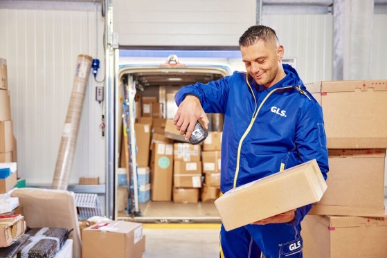 A GLS employee in a warehouse scans a package he is holding.